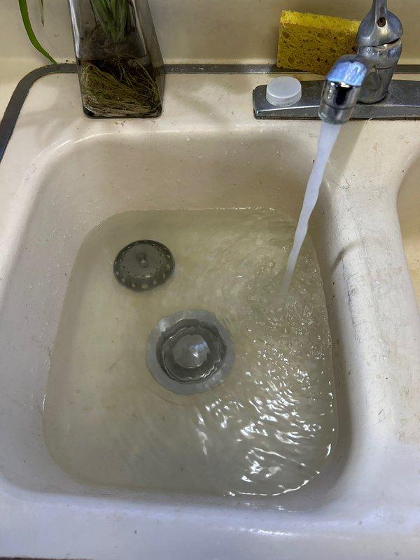 Responded to service call for slow-draining 5-6 year old garbage disposal. Diagnostics revealed clog in the drain line causing water to back up into the sink basin. Successfully removed blockage and verified proper drainage by testing water flow. All components now functioning correctly with no leaks observed.