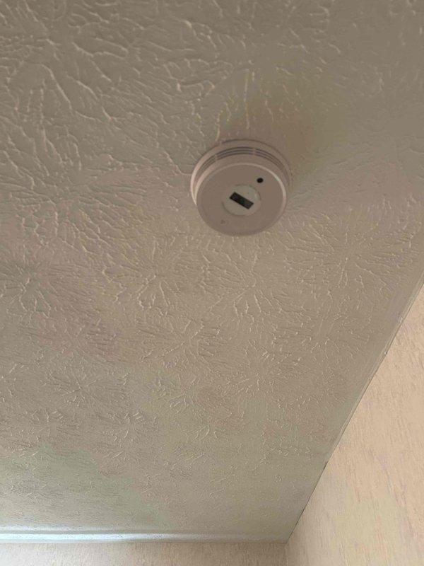 Successfully installed seven battery-operated interconnected smoke/carbon monoxide detectors throughout the residence. Units were properly mounted on textured ceilings and tested to verify interconnection functionality. All detectors were confirmed operational with indicator lights functioning correctly.