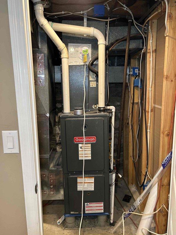 Inspected residential HVAC system with reported condensation issues in ductwork. Examined the Goodman furnace unit and surrounding PVC vent piping in the utility area, then evaluated existing duct insulation in the finished basement. Recommended additional insulation wrapping for exposed ductwork to prevent condensation buildup, particularly on the main runs mounted along ceiling joists.