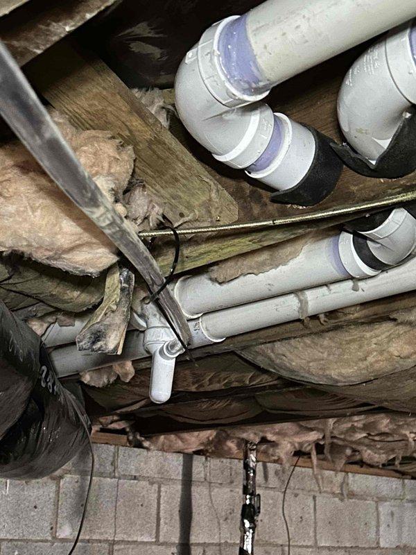 Investigated continuing knocking noise issue despite previous repair attempt that addressed flue pipe binding against joists. Inspected condensate drainage system and identified improper drainage in collection pan with visible moisture accumulation. Secured loose pipe connections and repositioned piping to eliminate movement during thermal expansion/contraction cycles, resolving the persistent knocking sound.