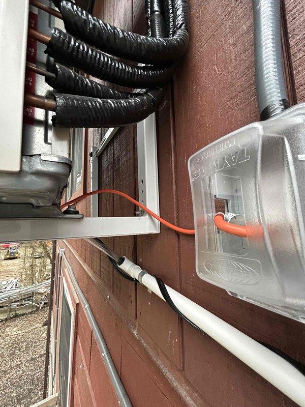 Completed warranty installation of ODU drain kit to address water drainage issues. Installed drain plug connector at active drainage point, extended with PVC pipe secured along exterior wall, and connected to existing condensate line. Added heat tape along entire drain line with weatherproof 120V receptacle installed off disconnect to prevent freezing.