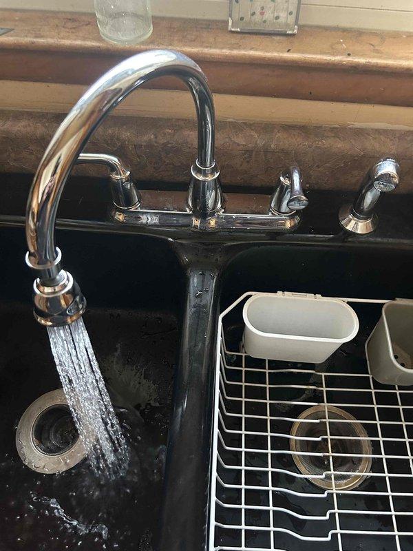 Responded to service call for kitchen faucet issue. Upon inspection, found faucet was operational with water flowing properly through the chrome high-arch fixture. No visible leaks were detected during testing of both the main water flow and sprayer attachment. All faucet components were confirmed to be functioning correctly with no repair needed.