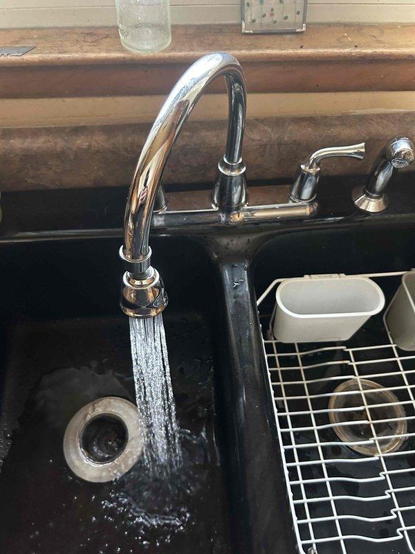 Responded to service call for kitchen faucet issue. Upon inspection, found faucet was operational with water flowing properly through the chrome high-arch fixture. No visible leaks were detected during testing of both the main water flow and sprayer attachment. All faucet components were confirmed to be functioning correctly with no repair needed.
