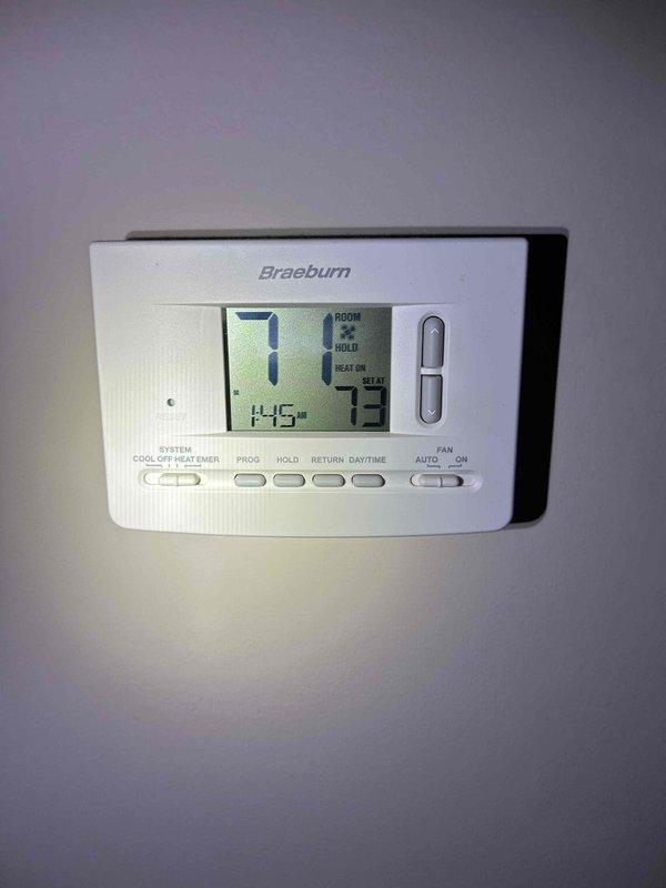 Responded to customer concern of abnormally high electricity consumption from heat pump system. Inspected Braeburn programmable thermostat which was functioning normally (set to 71°, reading 73° with heat mode active). Examined interior wiring connections and found significant dust accumulation and aging wire insulation in the control board area. Cleaned connections and verified proper operation of the heat pump system, confirming it was functioning as designed with no electrical issues detected.