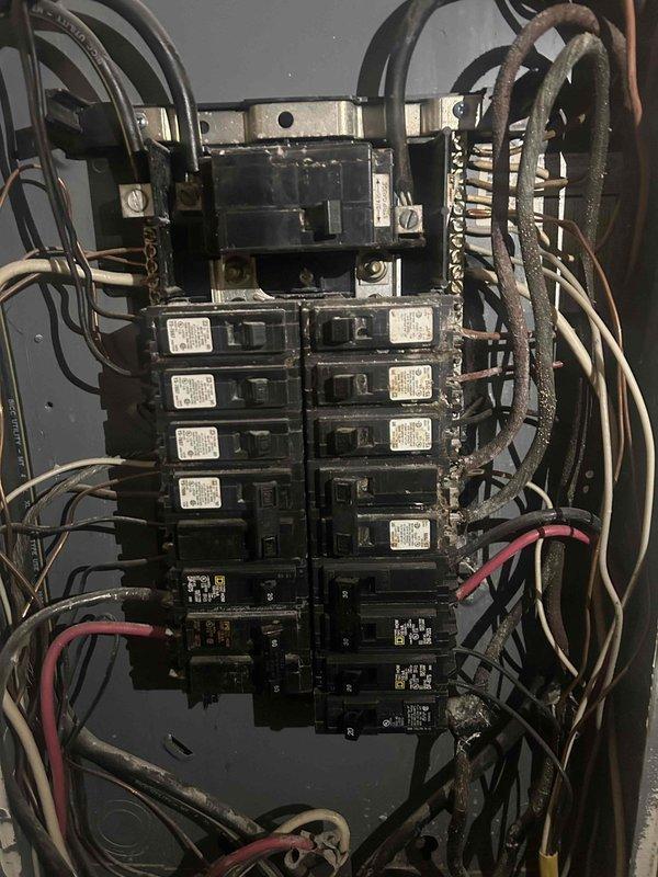 Completed electrical assessment for customer's multiple code compliance projects required by KU. Performed inspection of main electrical distribution panel which showed aging wiring, cluttered wire bundles, and mixed breaker types. Panel exhibited signs of wear with various wire gauges and inconsistent organization that would need to be addressed to meet current electrical standards.
