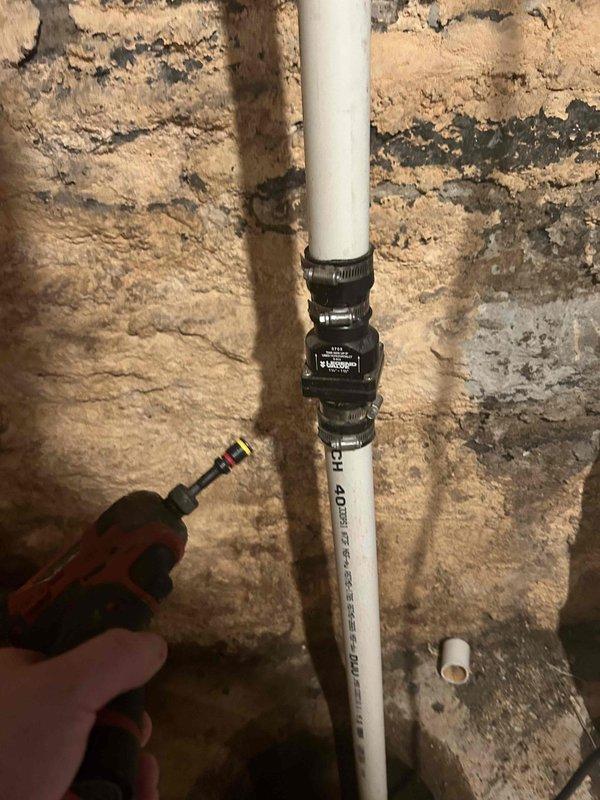 Responded to service call for sump pump repair. Found broken discharge pipe requiring reattachment. Installed new PVC pipe with Legend model 0703 coupling (1¼" - 1½") secured with metal hose clamps to reconnect the discharge line from sump pump to outside drainage, successfully resolving basement water leakage issue.