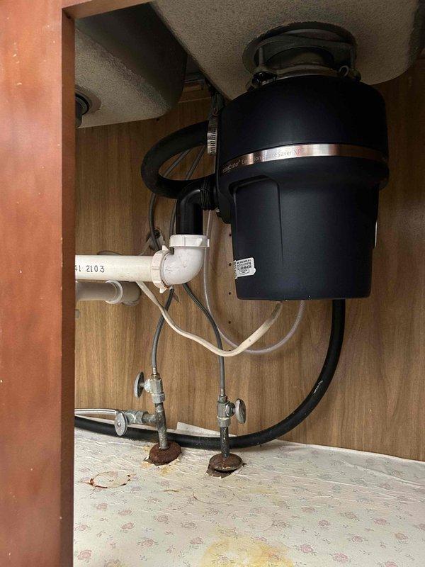 Conducted assessment of kitchen sink area for garbage disposal removal and replacement of sink and faucet. Observed existing disposal unit with signs of corrosion at water supply valve connections and evidence of previous water leakage on cabinet floor. Customer has supplied new fixtures for installation. Service quote provided and customer approval pending for scheduled return visit to complete the replacement work.