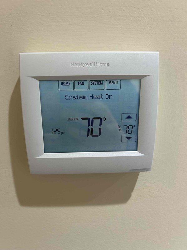 Diagnosed heat pump system experiencing intermittent no-heat condition. Verified Honeywell thermostat was properly calling for heat at 70°F setpoint but system was delivering cool air despite indicating auxiliary heat mode. Inspection of zone controller (HZ432) in attic revealed improper sequencing between primary and auxiliary heat stages. Recalibrated staging parameters and verified proper discharge air temperature (83°F) at zone 1. System now operating correctly with appropriate heat delivery.