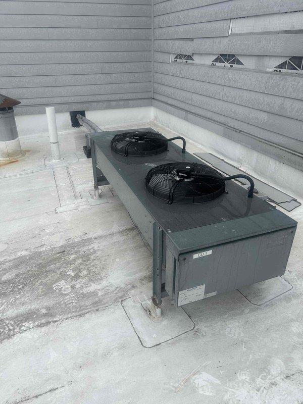 Responded to IAQ service call for a whole home humidifier issue with reported coil problems. Inspected outdoor HVAC unit with dual fan configuration and associated drainage system. Examined digital control panel which displayed "Dehum - Heat" and "Compressor On" status indicators, confirming system was actively running dehumidification cycle with compressor engagement.
