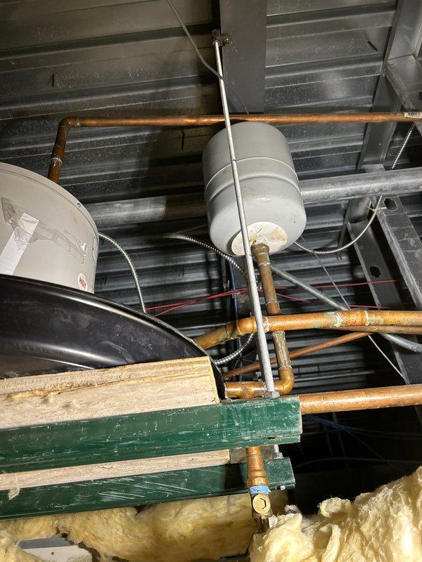 Inspected ceiling-mounted commercial water heater system in break room. Identified aging expansion tanks and copper piping with significant oxidation. Unit (approximately 10 gallons) was non-operational with no hot water output. Documented condition with photos showing deteriorated components and installation configuration for further assessment.