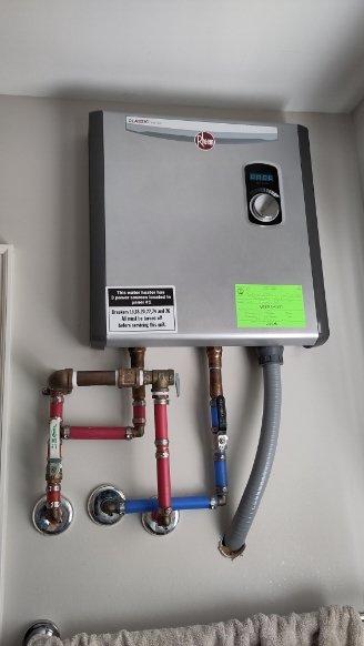 Performed assessment of two Rheem tankless water heaters requiring isolation valve installation. First unit located on first floor bathroom, second unit on second floor bathroom. Both units feature copper piping connections with existing valves. Documented current installation configuration with photographs to develop appropriate isolation valve solution as requested by customer.