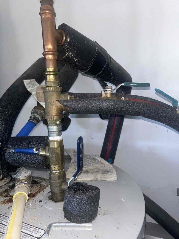 Conducted inspection of customer's water heater system to diagnose recurring annual leak. Examined plumbing connections including brass valves, copper piping, and insulated lines. Identified signs of corrosion at brass fittings and junction points that could be contributing to the persistent leakage issue. Recommended replacement of deteriorating components to prevent future water damage.