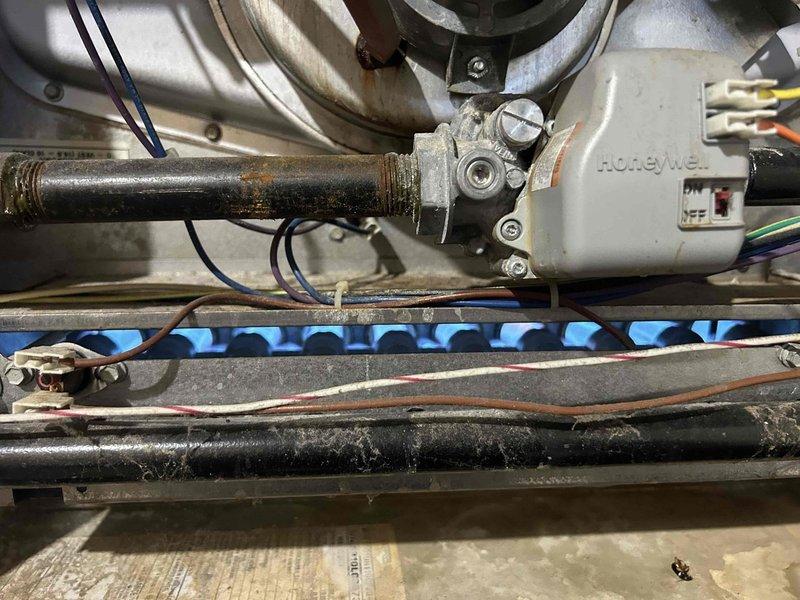 Responded to no-heat complaint on 14+ year old gas furnace that was shutting down after approximately one minute of operation. Diagnostic testing with manometer revealed gas pressure reading of 100, indicating proper supply to the unit. Visual inspection of burner assembly showed normal blue flames, but identified significant corrosion and rust on gas line connection to Honeywell control valve. Cleaned corroded connections, verified proper operation of control module, and restored system functionality with continuous operation through multiple test cycles.