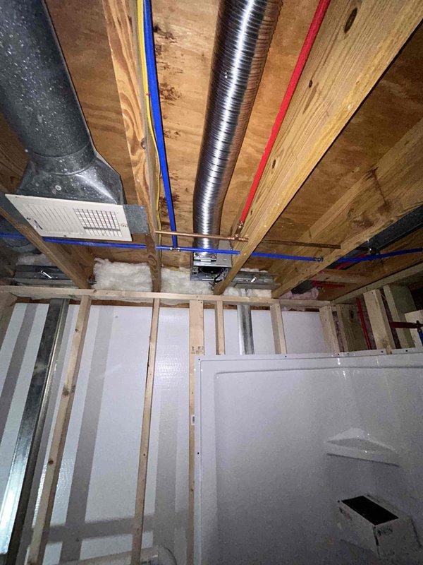 Completed final phase of basement bathroom installation project, including setting the shower base with proper drainage and connecting PEX water supply lines. Finalized plumbing rough-in work within the framed wall cavity, ensuring all connections were secure and properly aligned with the ventilation system prior to client's planned wall completion.