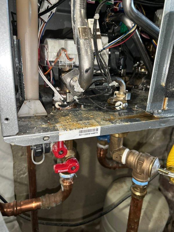Responded to service call for a leaking tankless water heater. Upon inspection, discovered water leakage coming from internal plumbing connections. Accessed the unit's interior components, examined copper pipes and brass fittings, and identified loose connection points within the system. Tightened all connections and verified proper operation with no further leakage detected.