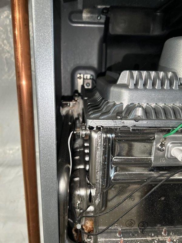 Responded to service call for a leaking tankless water heater. Upon inspection, discovered water leakage coming from internal plumbing connections. Accessed the unit's interior components, examined copper pipes and brass fittings, and identified loose connection points within the system. Tightened all connections and verified proper operation with no further leakage detected.