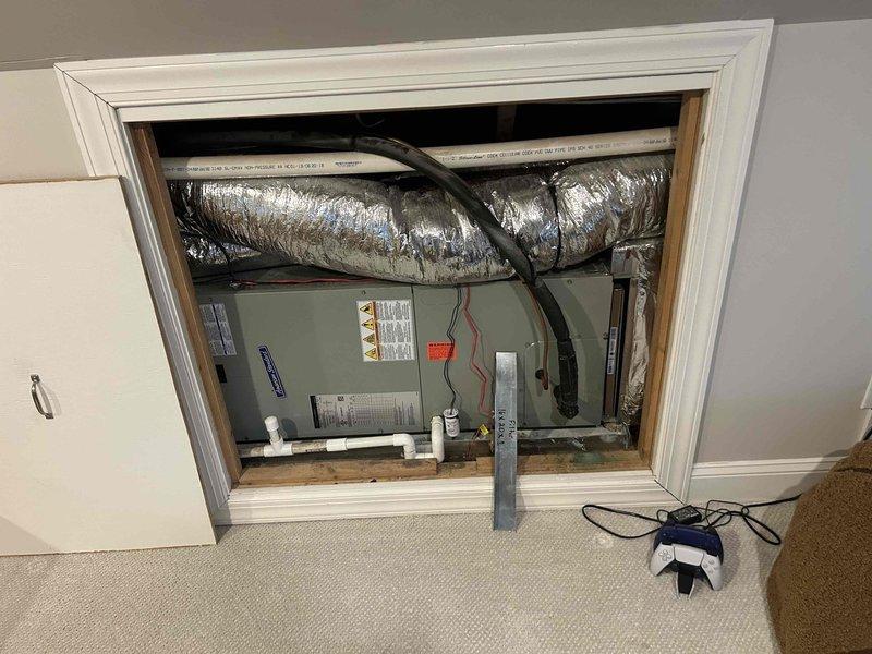 Conducted site evaluation for media cabinet installation request. Inspected existing HVAC system components including wall-mounted air handler with flexible ductwork and drain lines. Examined attic space containing main unit mounted on wooden platform with insulated silver ductwork running throughout. Documented current configuration with photos for estimate preparation.