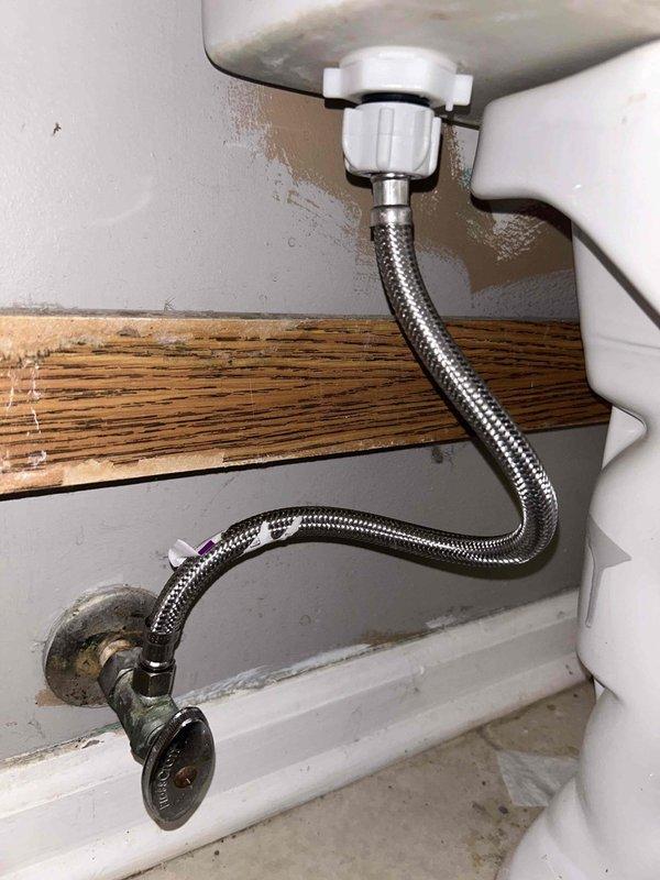 Responded to service call for toilet malfunction where water was spraying during use. Inspection revealed corroded supply line connection with visible water damage on surrounding wall. Replaced damaged braided supply line and valve assembly, resolving the leak issue. Tested toilet operation to confirm proper function with no water spray.