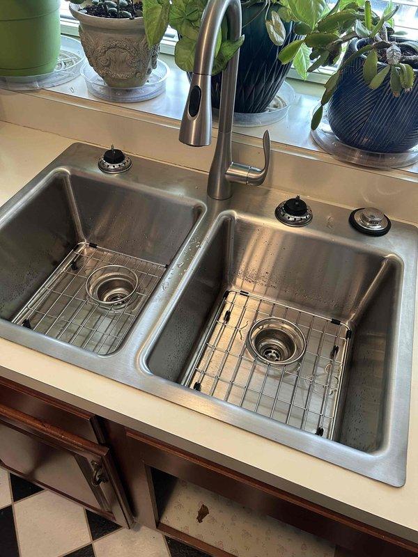 Successfully removed existing kitchen sink setup and installed customer-supplied double-basin stainless steel sink, contemporary faucet with pull-down sprayer, and garbage disposal. Completed proper P-trap configuration with PVC drain pipes for the double basin system and verified leak-free operation and functionality of all components before completion.