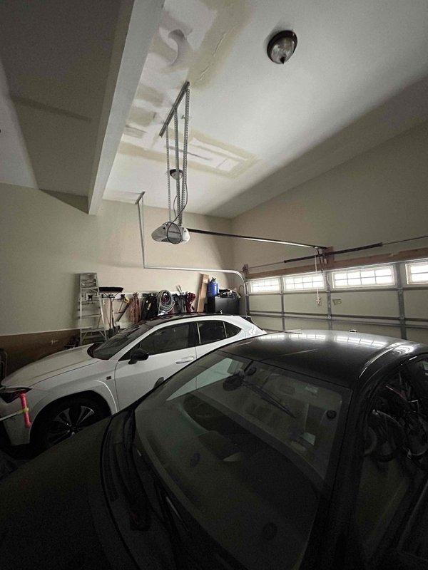 Responded to water leak emergency in garage ceiling caused by customer's use of space heater in room above garage during suspected pipe freeze. Visual inspection revealed water stains on garage ceiling and confirmed flooding had occurred but active leaking had stopped. Documented damage with photos showing affected ceiling area above two parked vehicles and adjacent storage.