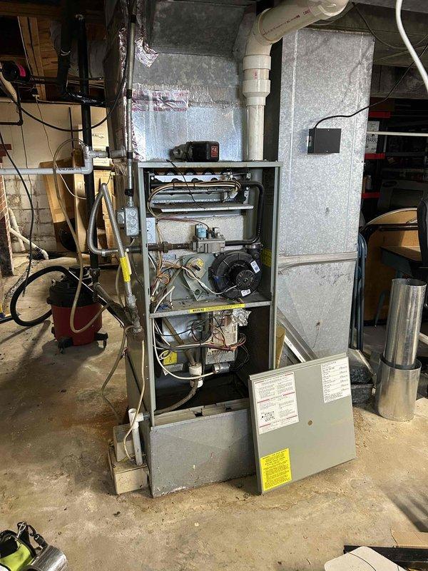 Responded to non-urgent service call for a 30-year-old furnace producing loud squealing noise. Upon inspection, removed access panel to examine internal components, focusing on the blower motor assembly which was identified as the source of noise. System was still operational but showing significant age-related wear on mechanical components.