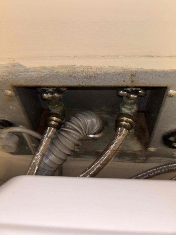 Conducted routine plumbing inspection of bathroom fixtures. Examined under-sink plumbing components including supply lines, shutoff valves, and P-trap configuration, which appeared properly installed with minor signs of aging. Identified significant bathtub damage with extensive brown discoloration/staining on the porcelain surface despite functional chrome faucet assembly and intact surrounding tile work.