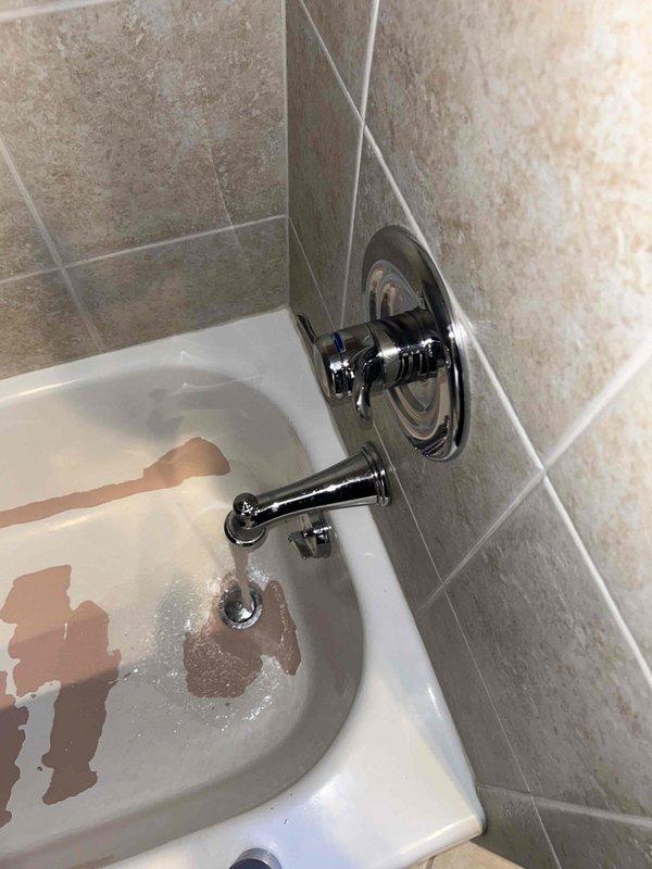 Conducted routine plumbing inspection of bathroom fixtures. Examined under-sink plumbing components including supply lines, shutoff valves, and P-trap configuration, which appeared properly installed with minor signs of aging. Identified significant bathtub damage with extensive brown discoloration/staining on the porcelain surface despite functional chrome faucet assembly and intact surrounding tile work.