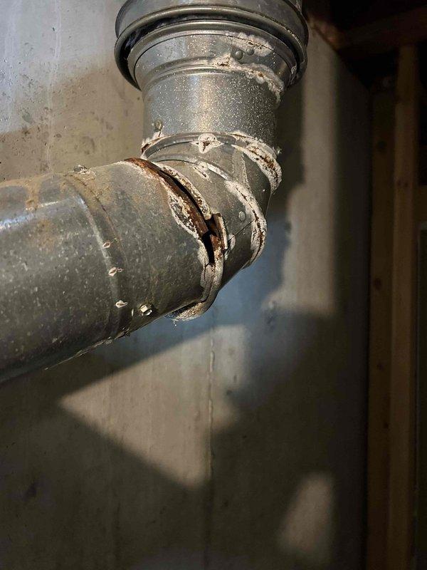 Responded to no heat call for 24-year-old furnace system. Diagnostic testing with UEI meter revealed error code E-1, indicating ignition failure. Inspection found significant corrosion and deterioration at exhaust pipe joint with attempted sealant repairs. Performed system evaluation and addressed pilot light ignition issue to restore heating function.