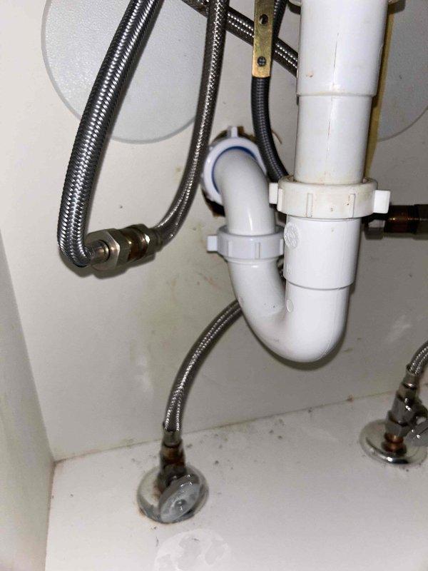 Successfully replaced damaged plumbing section by cutting into wall to access the problematic tee, removed affected pipe, and installed new PVC components. Post-installation testing confirmed proper water flow through the sink drain system with no leaks observed in the new P-trap assembly and supply line connections.