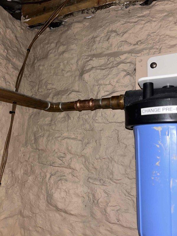 Diagnosed and replaced clogged whole-house water filtration system causing loss of pressure throughout the residence. Inspection revealed a severely fouled pre-filter in the main blue canister unit mounted on copper supply lines, restricting water flow. After replacement, system restored to normal operating pressure.