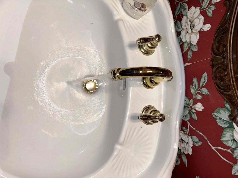 Conducted plumbing inspection per PSA request regarding detached shower knob. Examined bathroom fixtures including sink drainage functionality and water flow. Inspected brass shutoff valve and PVC drain pipe connections. Verified proper operation of sink drain system with no visible leaks in the plumbing components.