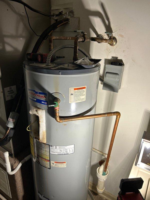 Responded to service call for leaking water heater with full drain pan. Upon inspection, determined unit required replacement. Installed new cylindrical tank-style water heater with appropriate copper pipe connections, pressure relief valve, and drain line. Completed electrical connections via junction box and verified proper operation of new unit.