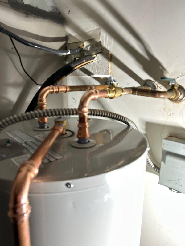 Responded to service call for leaking water heater with full drain pan. Upon inspection, determined unit required replacement. Installed new cylindrical tank-style water heater with appropriate copper pipe connections, pressure relief valve, and drain line. Completed electrical connections via junction box and verified proper operation of new unit.