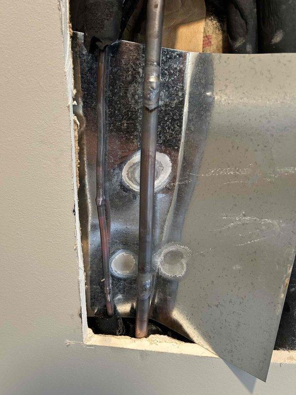 Responded to call back regarding leak issues during warmer conditions. Located and accessed plumbing components behind wall panel, inspected copper lines for corrosion and mineral buildup at connection points. Performed temperature differential testing on Dynastar wall-mounted unit, recording readings of 100.8°F/98°F to verify proper operation after leak repair.