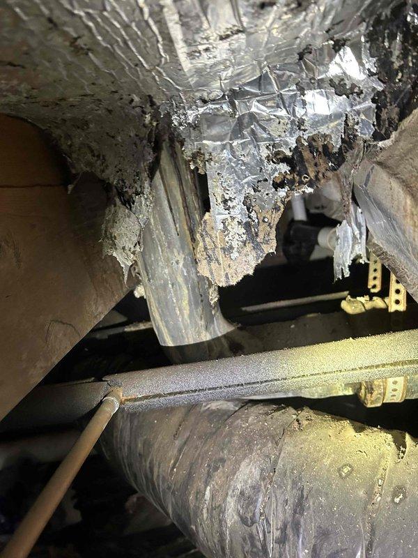 Inspected customer's crawlspace plumbing system and identified severely corroded brass pipe fittings with significant mineral buildup at connection points. Observed damaged insulation on nearby ductwork with torn foil backing. Recommended replacement of deteriorated pipe connectors to prevent potential leaks and system failure.