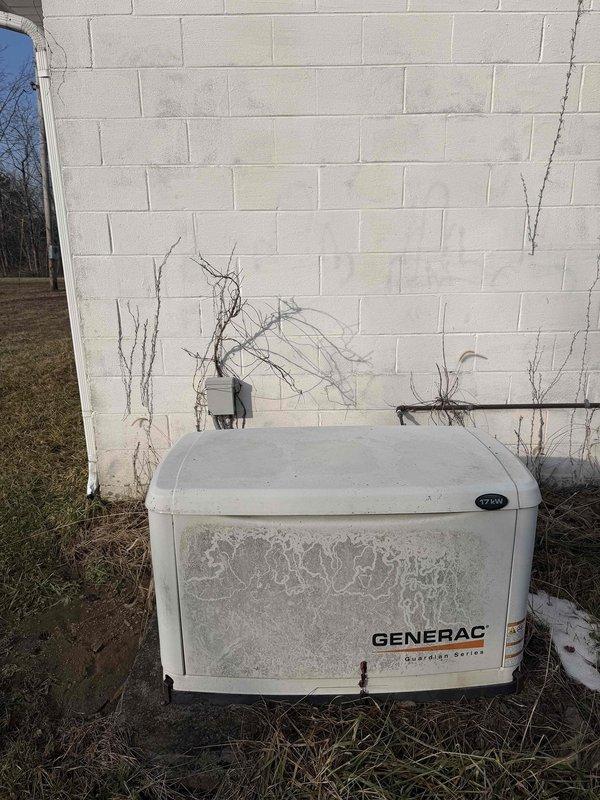 Performed scheduled maintenance on customer's Generac air-cooled backup generator. Inspected the exterior condition noting weathering and environmental buildup on the protective housing. Checked fuel level as per protocol. Observed significant corrosion on pressure gauge (reading 20-30) and deterioration of surrounding mounting surface, with visible rust and concrete fracturing that may require future attention.