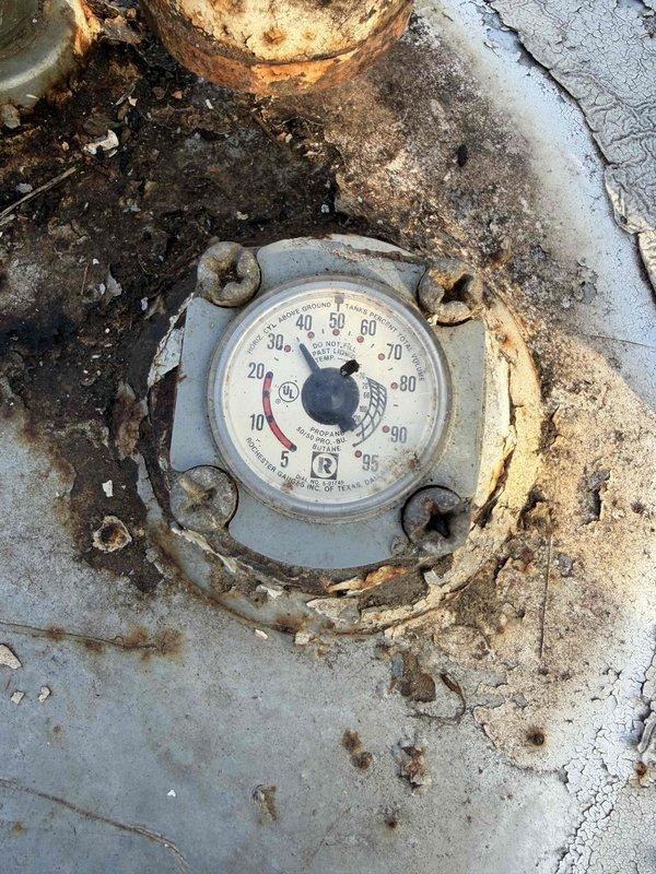 Performed scheduled maintenance on customer's Generac air-cooled backup generator. Inspected the exterior condition noting weathering and environmental buildup on the protective housing. Checked fuel level as per protocol. Observed significant corrosion on pressure gauge (reading 20-30) and deterioration of surrounding mounting surface, with visible rust and concrete fracturing that may require future attention.