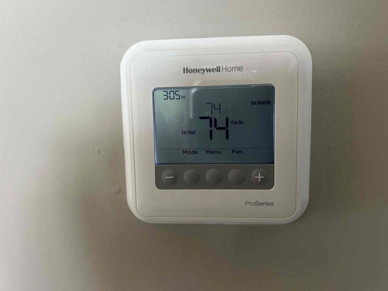 Responded to no heat service call for 6-7 year old heat pump system. Found system operating in emergency/auxiliary heat mode with indoor temperature at 74°F despite thermostat indicating "Em Heat On." Conducted temperature diagnostic at supply vent registering 73.8°F. Unit inspection revealed completely frozen fan blades requiring additional diagnosis; will return to complete repair after customer approval.
