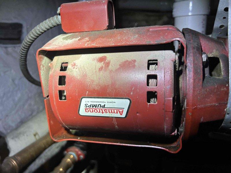 Responded to water leak service call for a Weil-McLain boiler system. Upon inspection, identified pooling water beneath the unit in basement mechanical room. Diagnosed faulty Armstrong circulation pump showing signs of wear and leakage. Repaired pump connection and verified proper system operation with no further water accumulation.