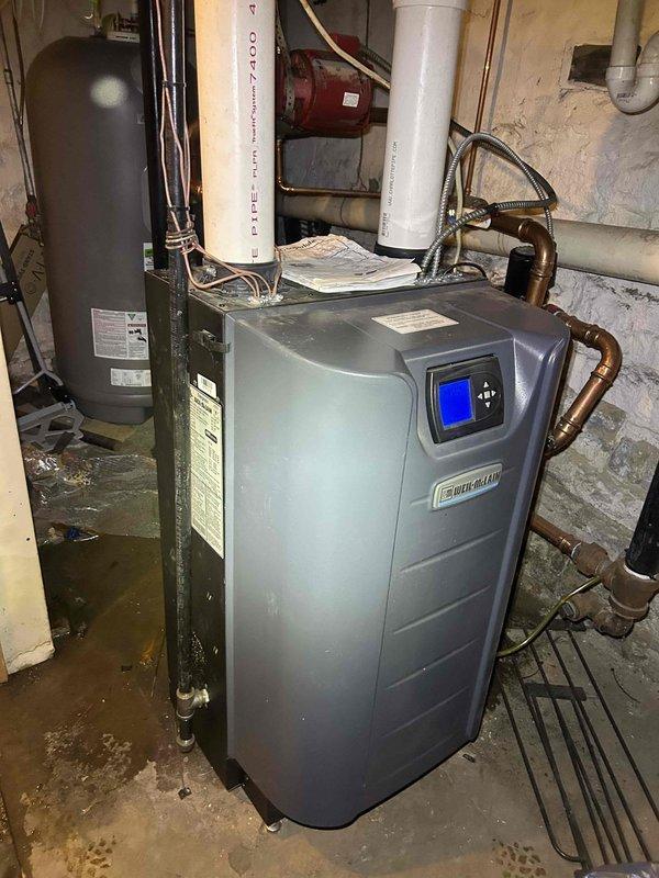 Responded to water leak service call for a Weil-McLain boiler system. Upon inspection, identified pooling water beneath the unit in basement mechanical room. Diagnosed faulty Armstrong circulation pump showing signs of wear and leakage. Repaired pump connection and verified proper system operation with no further water accumulation.