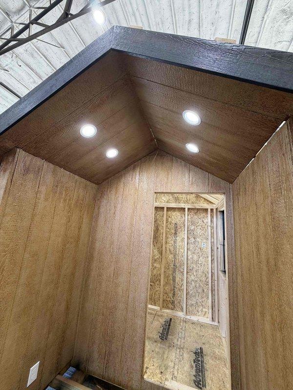 Completed installation of four 4" LED wafer lights in wooden ceiling, along with one GFCI outlet, two single-pole switches, and one weatherproof box with receptacle and cover. Ran SJ cord with male cord cap for power connection. Electrical rough-in work was performed in wood-paneled space with OSB sheathing prior to final finishing.