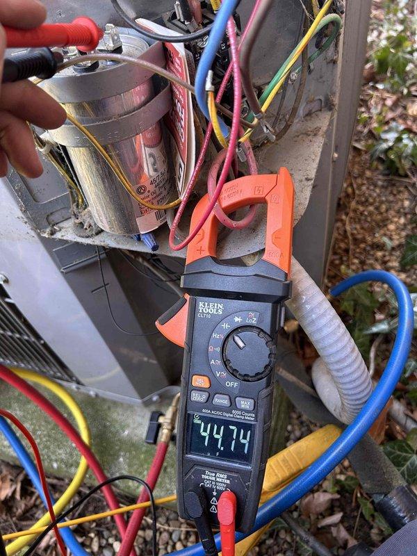 Performed scheduled maintenance on residential AC system located in basement. Conducted electrical diagnostic testing using clamp meter, measuring amperage at 44.74A. Inspected capacitor connections and found moderate dust accumulation and cobwebs; verified all colored wiring terminals were secure with no signs of overheating or damage.