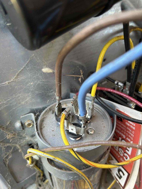 Performed scheduled maintenance on residential AC system located in basement. Conducted electrical diagnostic testing using clamp meter, measuring amperage at 44.74A. Inspected capacitor connections and found moderate dust accumulation and cobwebs; verified all colored wiring terminals were secure with no signs of overheating or damage.