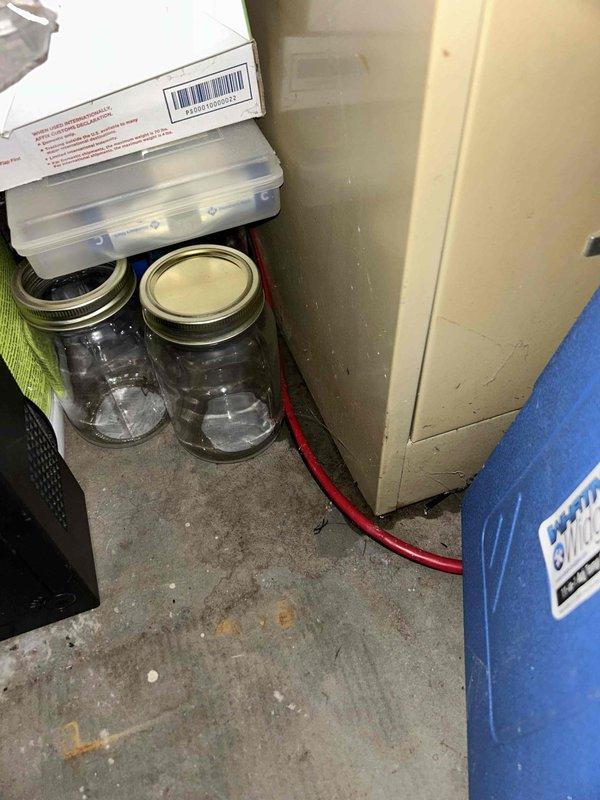 Responded to water leak service call and identified that the condensate drain pipe from the furnace was approximately 0.5-1.5 inches too short, causing steady water leakage into the utility room and garage area. Documented moisture damage to concrete floor and surrounding materials with visible staining and deterioration. Extended drain pipe to proper length to eliminate the ongoing leak issue.