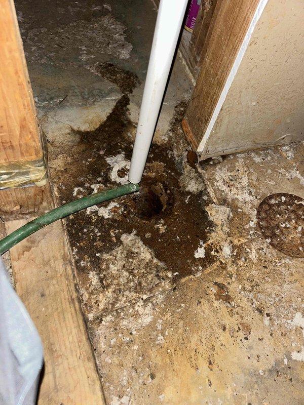 Responded to water leak service call and identified that the condensate drain pipe from the furnace was approximately 0.5-1.5 inches too short, causing steady water leakage into the utility room and garage area. Documented moisture damage to concrete floor and surrounding materials with visible staining and deterioration. Extended drain pipe to proper length to eliminate the ongoing leak issue.