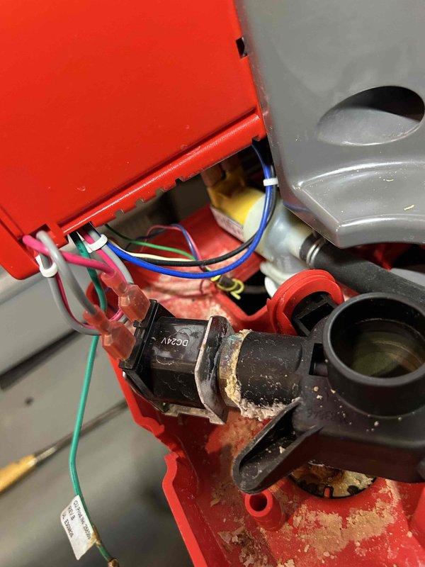 Responded to customer-reported whole-house humidifier malfunction. Upon inspection, discovered significant mineral buildup and corrosion within the red housing assembly, particularly affecting the electrical connections and valve marked "N290". Determined the issue was due to mineral accumulation rather than improper installation, and performed necessary cleaning and component replacement to restore proper humidifier operation.