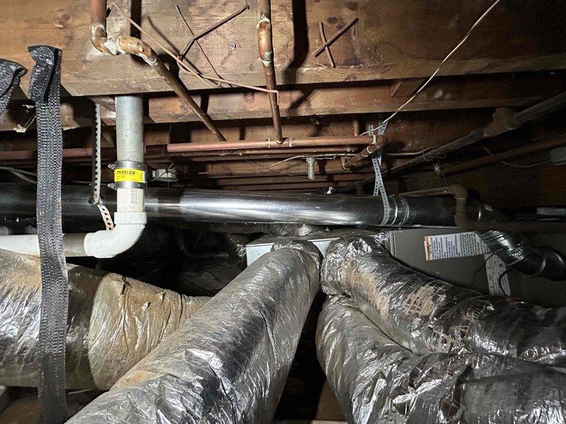 Completed warranty inspection of HVAC installation, focusing on furnace flue components. Documented installation compliance via photographic evidence of component labeling (PN: 4-M90) and crawl space ductwork with proper insulation. Additional flue inspection photos pending as requested.