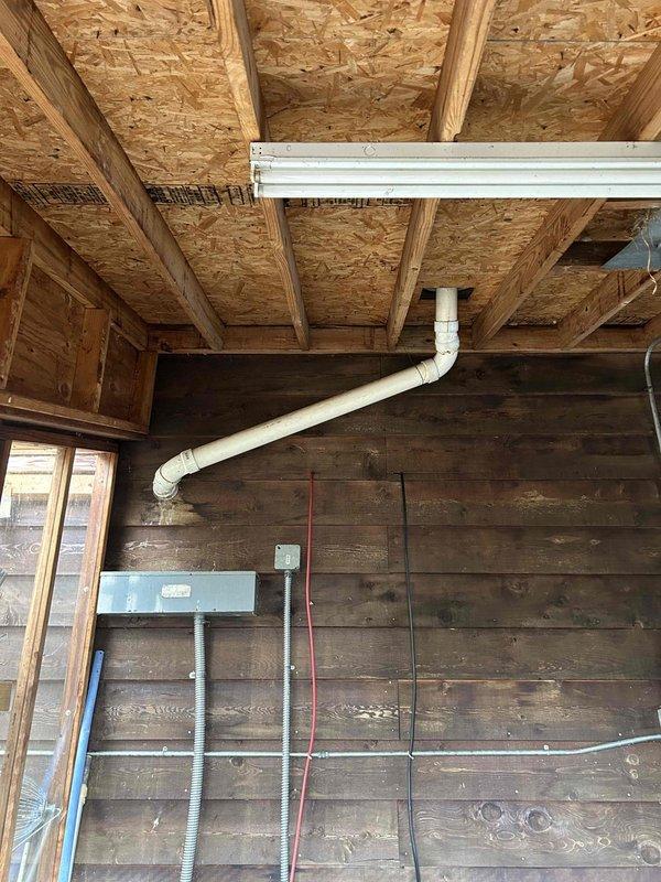 Inspected HVAC condensate line in garage exhibiting significant backup issues. Identified deteriorated PVC piping with visible rust staining and water damage to surrounding wooden structures. Repaired disconnected section of condensate drainage system and addressed pooling water issue to restore proper drainage functionality.
