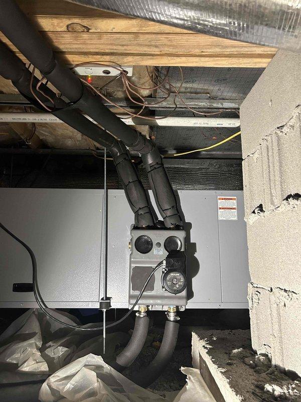 Returned to complete HVAC system installation in basement/crawl space. Installed air handler/furnace unit against concrete block wall with proper ductwork connections and electrical components. Documented installation with photos showing completed system with insulated ducts, control panel, and electrical connections.