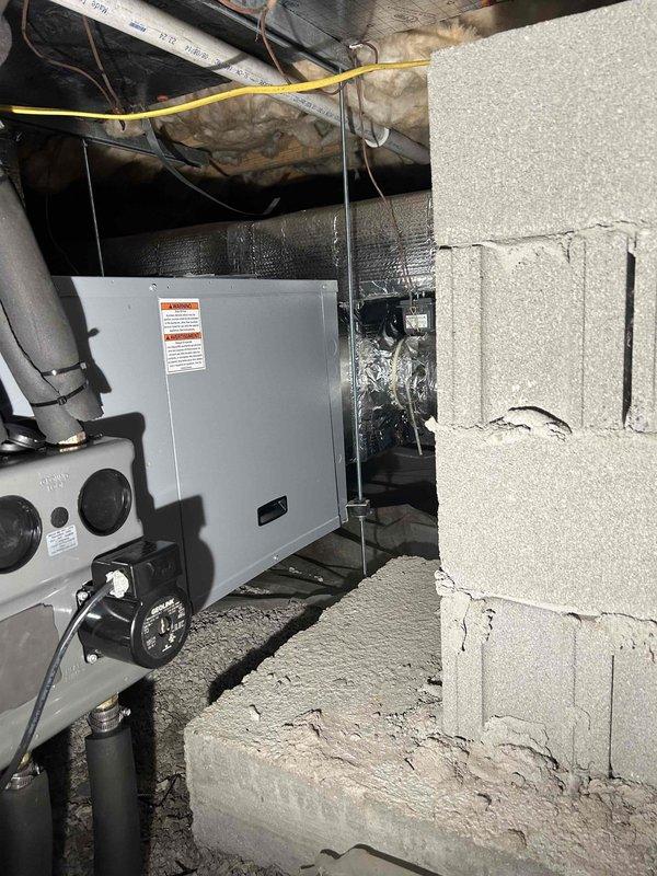 Returned to complete HVAC system installation in basement/crawl space. Installed air handler/furnace unit against concrete block wall with proper ductwork connections and electrical components. Documented installation with photos showing completed system with insulated ducts, control panel, and electrical connections.